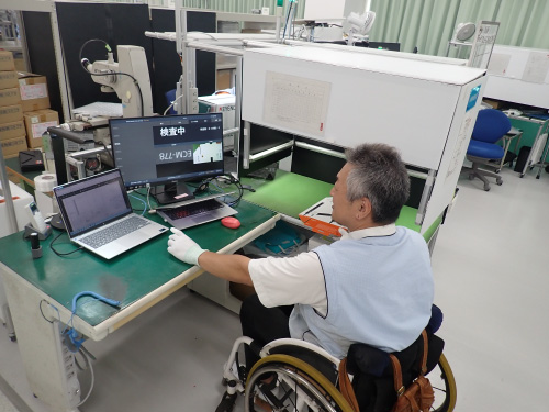 車いすの社員がパソコンの画面で検査を行っている様子