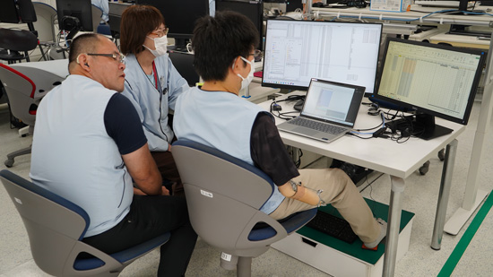 3名の社員がパソコンを囲んでミーティングを行っている様子