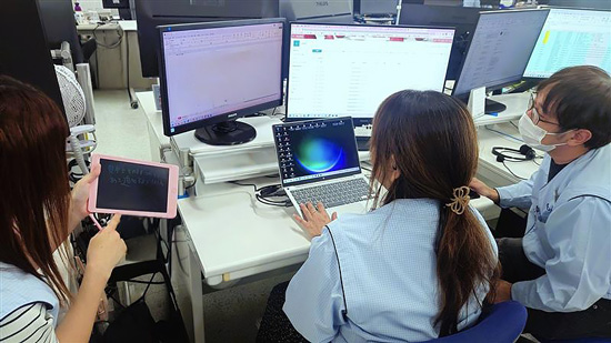 3名の社員がパソコンを囲んでミーティングをしている様子。