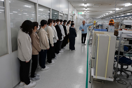 会社見学のグループに製造作業の説明をしている社員