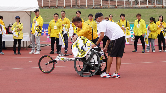 車いすマラソン大会でスタッフボランティアとして選手の車いすを押している社員