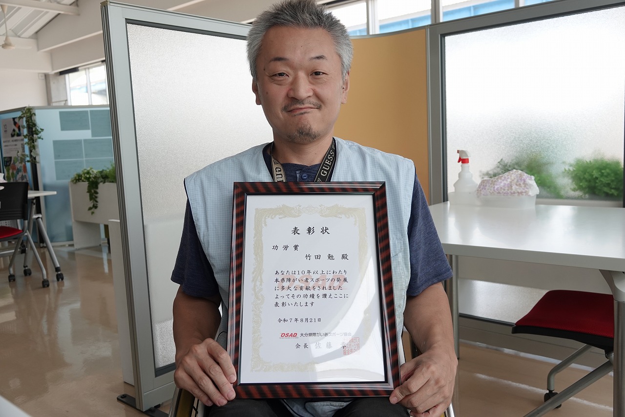 表彰状を手に持つ弊社社員の竹田勉さん