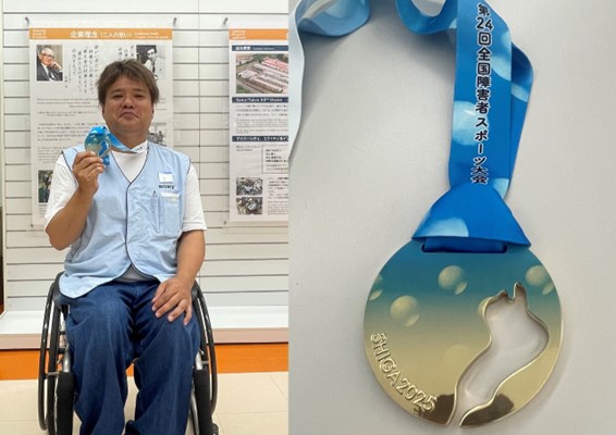 弊社社員の官野光一さん（車いすユーザー）が金メダルを手に持っている様子