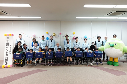 新入学生の９名の児童と親御さんと社員の集合写真
